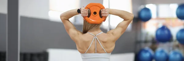 Sportswoman does exercises on muscles of the back with round dumbbell — Fotografia de Stock