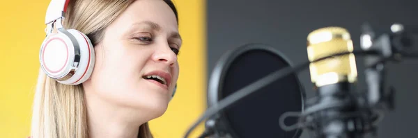 Portrait of singing woman in headphones in front of microphone — стоковое фото