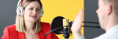 Kulaklıklı genç bir kadın radyo istasyonunda röportaj yapıyor.