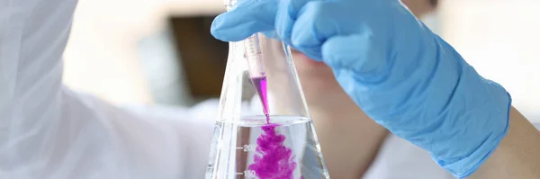 Scienziato chimico aggiungendo reagente al pallone di vetro con primo piano acqua — Foto Stock