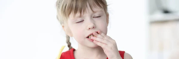 闭上双眼的小女孩吃着美味的薯条 — 图库照片
