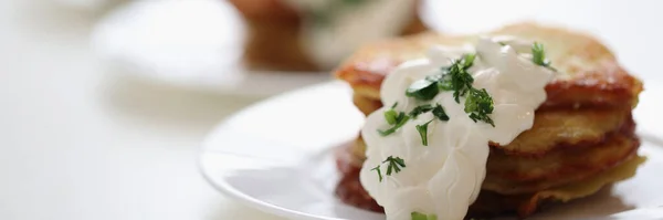 Panqueques de patata apetitosos con salsa de crema agria y eneldo acostado en el plato — Foto de Stock