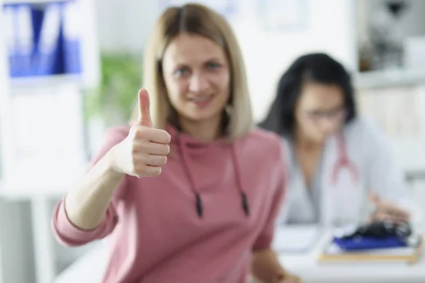 Пациентка держит большие пальцы на приеме у врача — стоковое фото