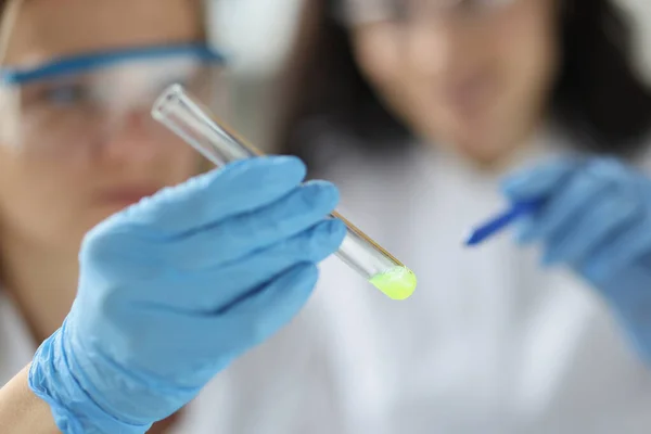 Cientista mostra tubo de ensaio com substância amarela em laboratório — Fotografia de Stock