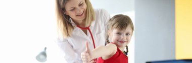 Pediyatrist doktor steteskopla küçük kızın nefesini dinler.