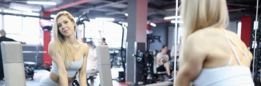 Genç sporcu spor salonunda ağır dambıllar alır.