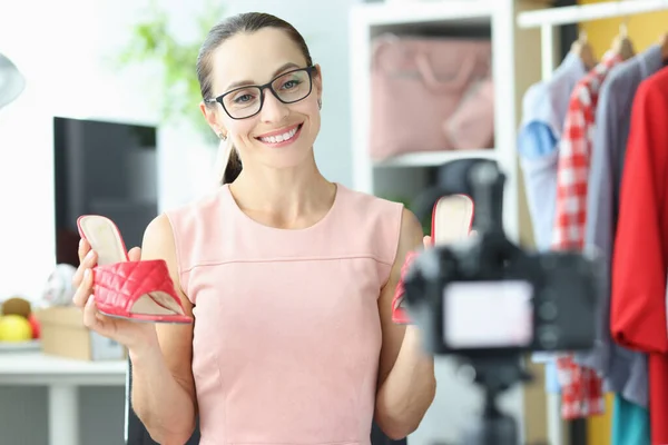 Жінка в окулярах, показуючи червоні босоніжки на камеру — стокове фото
