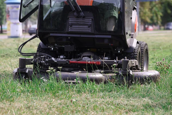 Тракторная газонокосилка косит траву в парке крупным планом — стоковое фото