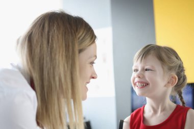 Kadın konuşma terapisti küçük bir kızla konuşuyor.