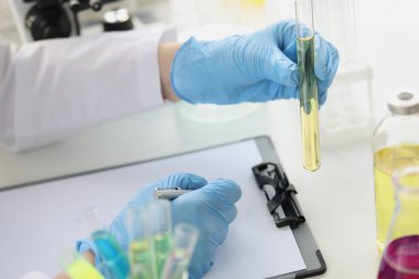 Bilim adamı test tüpünde saydam sıvının laboratuvar testlerini yürütüyor.