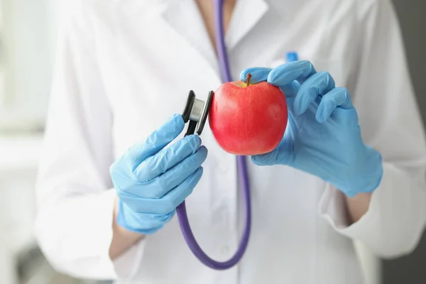 Доктор держит стетоскоп и спелое красное яблоко крупным планом — стоковое фото