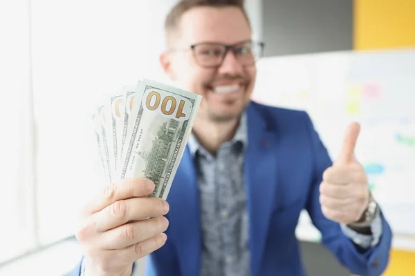 Glimlachende zakenman houdt geld en duimen omhoog gebaar — Stockfoto