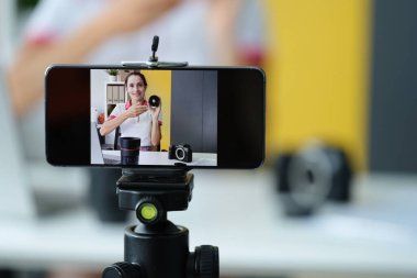 Kadın blogcu, yüksek kaliteli çekim için fotoğraf ekipmanları ve lenslerin incelemesini yürütüyor