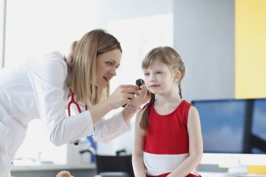 Doktor küçük bir kızın kulağını muayene ediyor.
