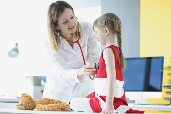 Médico pediatra escucha con estetoscopio a la respiración de niña en el consultorio médico — Foto de Stock