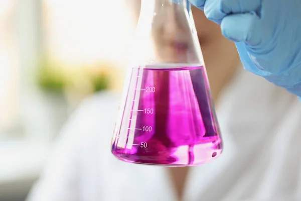 Badacz trzyma kolbę fioletowego płynu z rękawiczkami — Zdjęcie stockowe