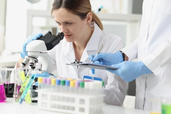 Equipe de cientistas realiza pesquisas laboratoriais usando microscópio — Fotografia de Stock