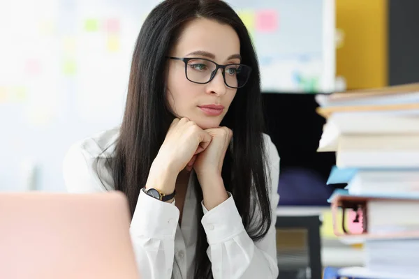 Sad businesswoman looks at large stack of folders with documents at workplace — Stock Photo, Image