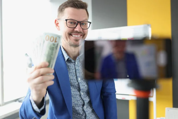 Smiling blogger demonstrates cash one hundred dollar bills to camera — ストック写真