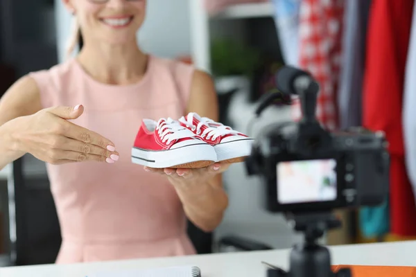 Консультант з продажу жінок показує камеру червоне спортивне взуття — стокове фото