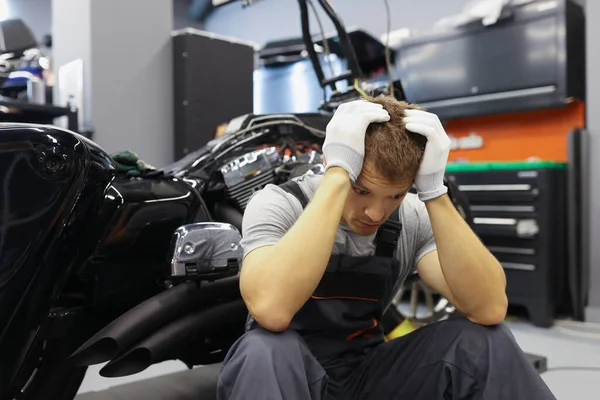Baş ağrısı olan usta çilingir benzin istasyonunda motosikletin yanında oturuyor. — Stok fotoğraf