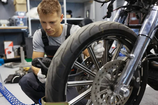 Muž kontroluje tlak pneumatik na motocyklu v dílně — Stock fotografie