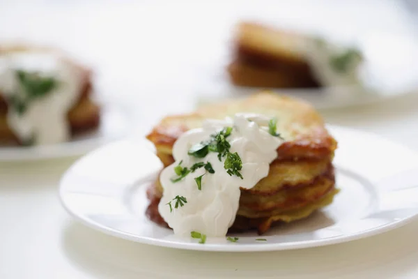 Panqueques de patata con crema agria y hierbas en el primer plano del plato — Foto de Stock