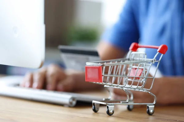 Vrouwelijke hand met toetsenbord en winkelwagentje close-up — Stockfoto