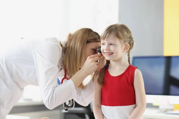 Kvinna barnläkare undersöker öra lilla flicka med otoskop på kliniken — Stockfoto