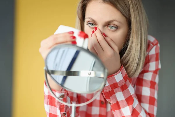Νεαρή γυναίκα σκουπίζει τη μύτη της με ιστό μπροστά στον καθρέφτη. — Φωτογραφία Αρχείου