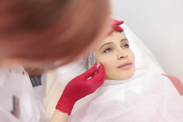 Schoonheidsspecialiste maken van permanente make-up voor oogleden en wenkbrauwen aan vrouw klant in schoonheidssalon — Stockfoto