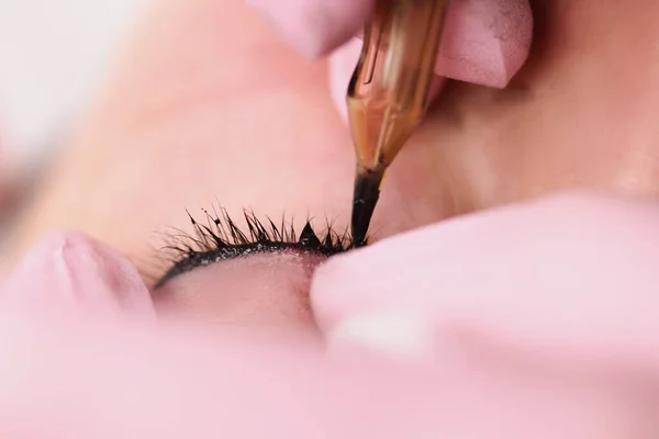 Maestro haciendo permanente maquillaje de espacio entre pestañas a cliente mujer en primer plano salón de belleza — Foto de Stock