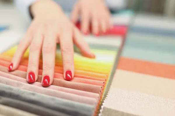 Vrouw met rode manicure kiezen stof voor naaien gordijnen closeup — Stockfoto