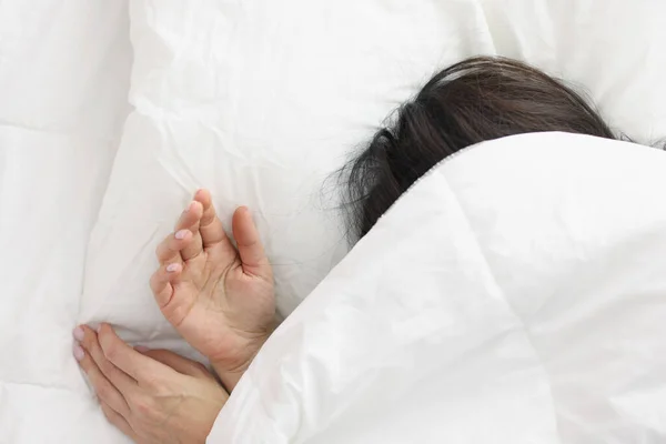 Mujer acostada en la cama bajo una manta blanca en el dormitorio —  Fotos de Stock