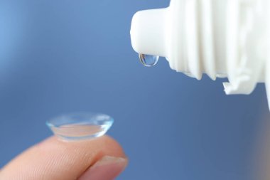 Şişeden damlayan şeffaf damlalar kontakt lenslerin yakınından geçiyor.