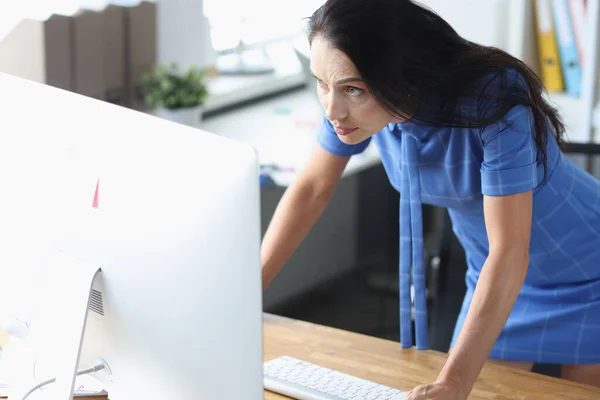 Vážná žena stojí před počítačem a dívá se na monitor — Stock fotografie