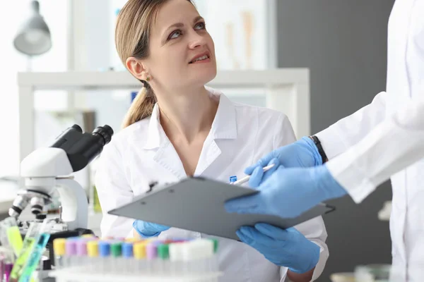 Wissenschaftler im Labor verwenden Mikroskop und zeichnen Ergebnisse in Nahaufnahme auf — Stockfoto