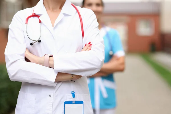 Doctors veterinarians stand confidently with folded hands on background of farm — Stock Photo, Image