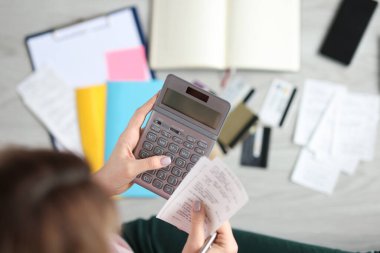 Kadın hesap makinesini tutuyor ve çekini yakın plan çekiyor.