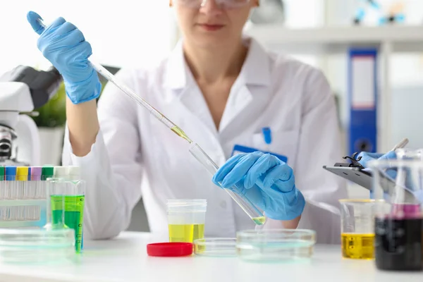 Cientista feminina realiza pesquisa sobre líquido amarelo transparente em close-up de laboratório — Fotografia de Stock