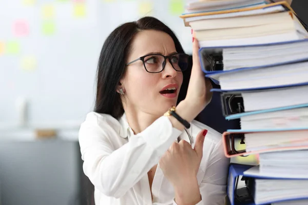 Verängstigte, aufgebrachte Frau blickt auf große Stapel von Arbeitspapieren in Großaufnahme — Stockfoto