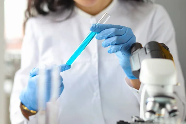 Wissenschaftlerhände in Handschuhen halten Reagenzglas mit blauer Flüssigkeit im Labor — Stockfoto