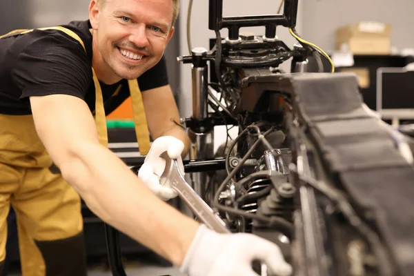 Usmívající se samec zámečník opravy motocykl s klíčem v servisním centru — Stock fotografie