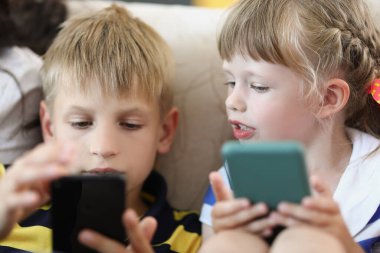 Erkek ve kız evde akıllı telefonları yakından izliyorlar.