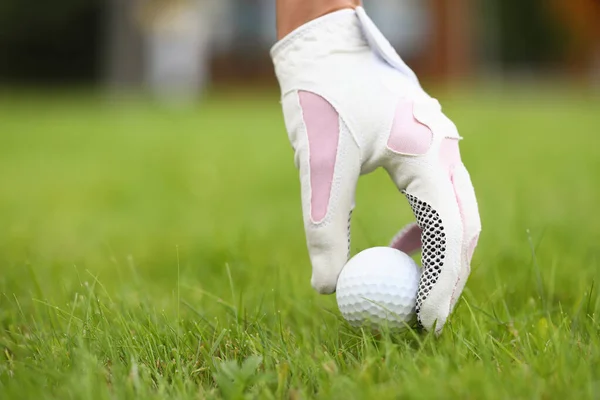 Egy kéz a kesztyűben golflabdát tesz a fűre. — Stock Fotó
