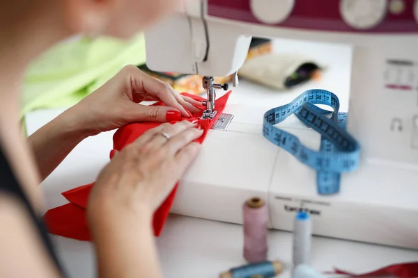 Woman sew on red fabric on a sewing machine — Stock Photo, Image