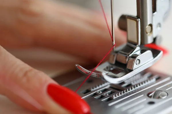 Handen trekken rode draad in naaimachine naald — Stockfoto