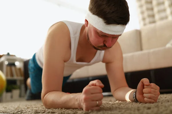 L'homme effectue des exercices de planche sur le tapis appartement — Photo