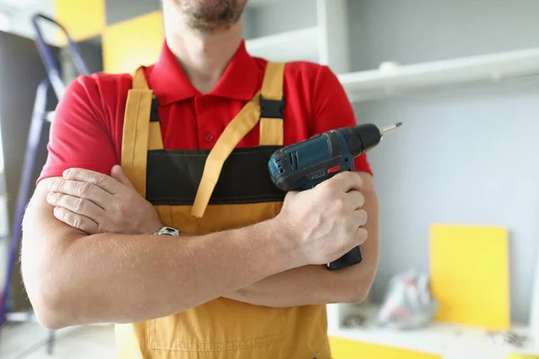 Um homem de roupa de trabalho tem uma pistola de parafuso — Fotografia de Stock