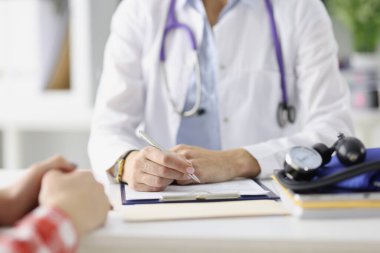 Doktor masada oturup tükenmez kalemle tıbbi kayıtları hazırlıyor.